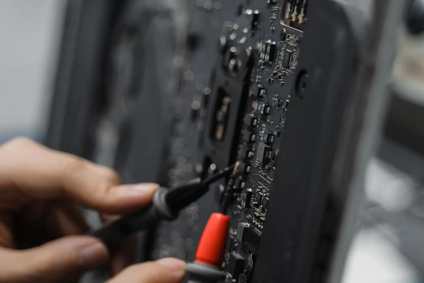 Teknisi memeriksa papan sirkuit smartphone dengan alat presisi
